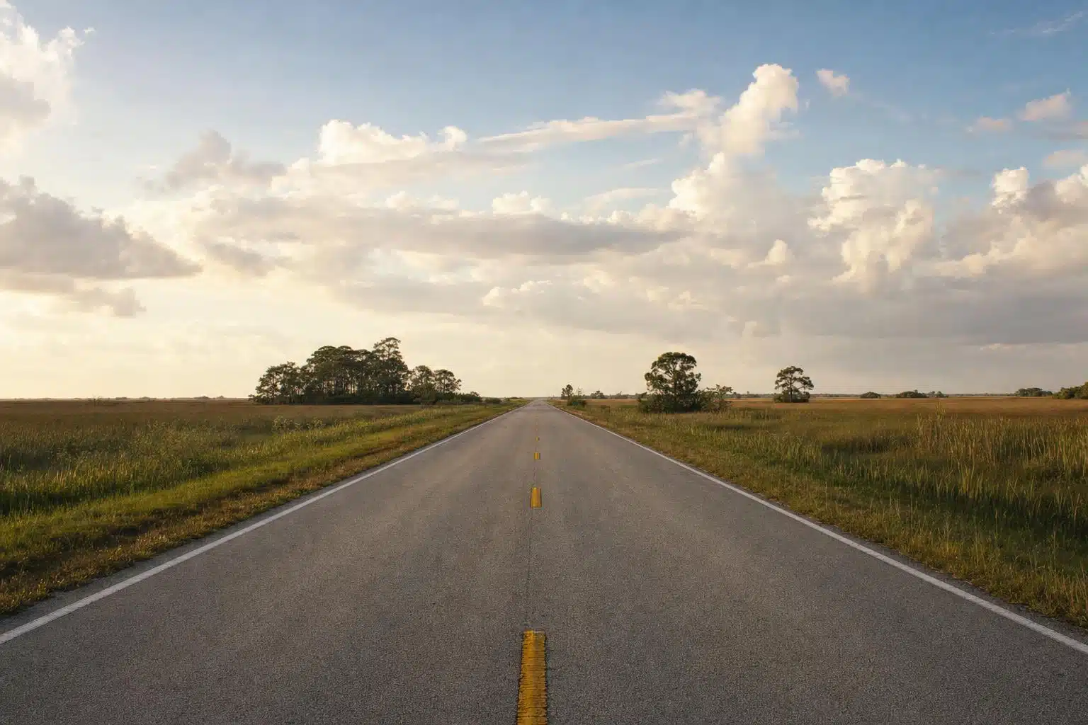 A two-lane road through the Everglades sawgrass prairie under a big sky (representative scene)