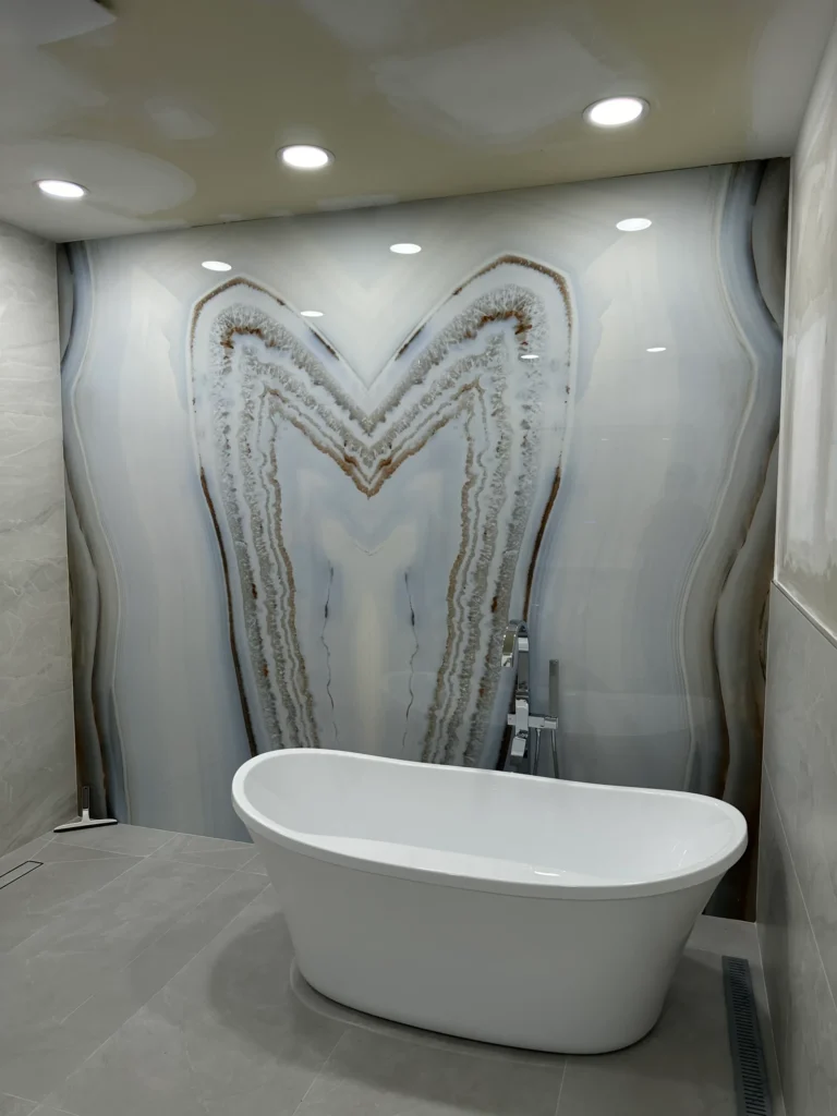 Freestanding soaking tub against a bookmatched stone look feature wall in a bathroom remodel by Alliance Construction in Southwest Florida Freestanding soaking tub against a bookmatched stone look feature wall in a bathroom remodel by Alliance Construction in Southwest Florida (Alliance Construction remodel, Southwest Florida)